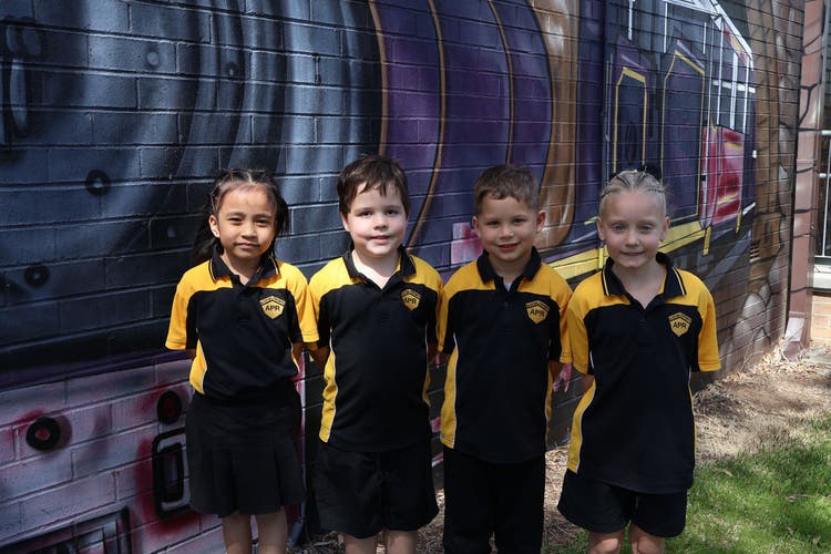 Four students standing in black and gold school uniform